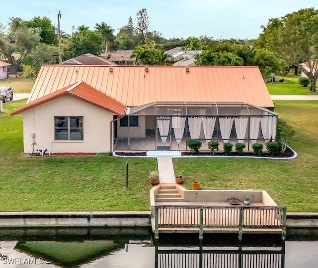 rear view of property featuring a yard and glass enclosure