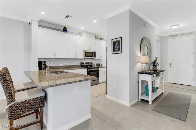 kitchen with kitchen peninsula, stainless steel appliances, white cabinets, ornamental molding, and sink