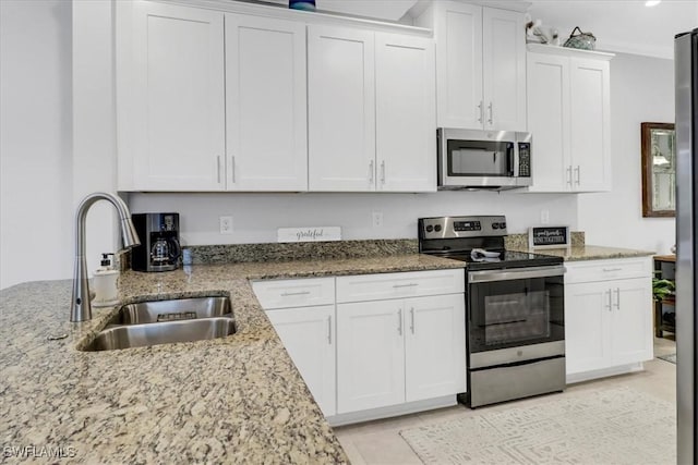 kitchen with sink, stainless steel appliances, white cabinetry, and light stone countertops