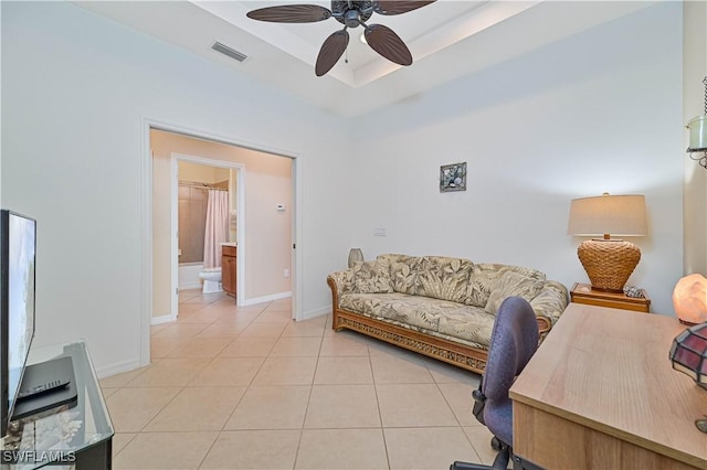 home office with a raised ceiling, ceiling fan, and light tile patterned floors