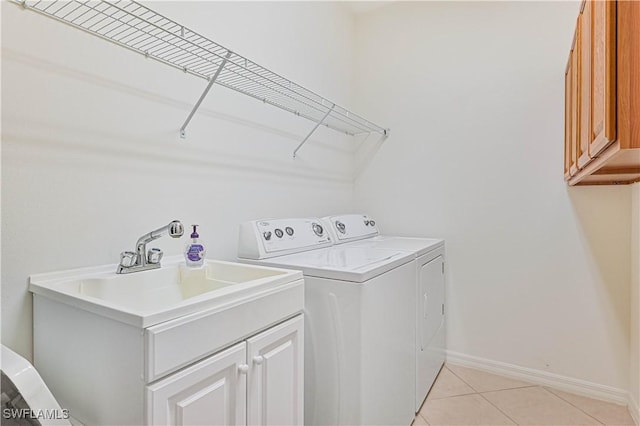 laundry room featuring cabinets, light tile patterned floors, and washing machine and clothes dryer