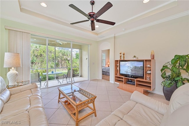 living room with ceiling fan, a raised ceiling, light tile patterned floors, and ornamental molding