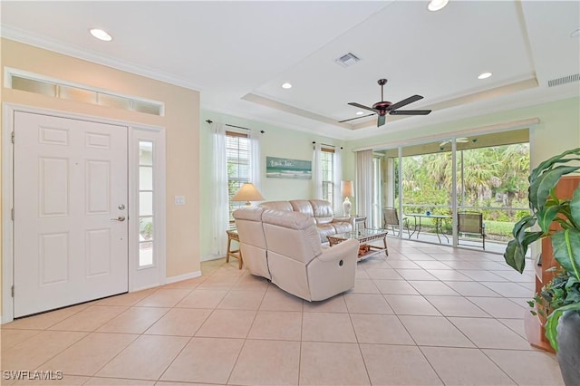 living room with a tray ceiling, ceiling fan, crown molding, and light tile patterned floors