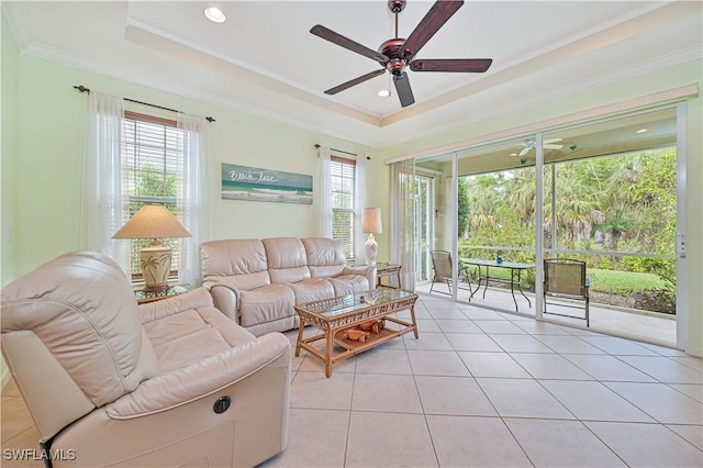 living room featuring a raised ceiling, ceiling fan, light tile patterned flooring, and ornamental molding