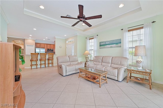 living room featuring ceiling fan, light tile patterned flooring, crown molding, and a tray ceiling