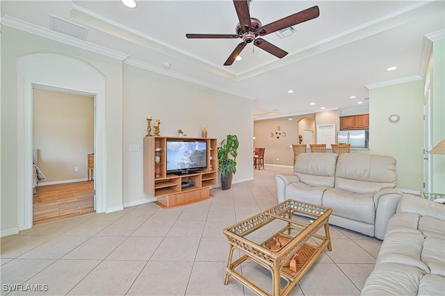 tiled living room with ceiling fan and crown molding