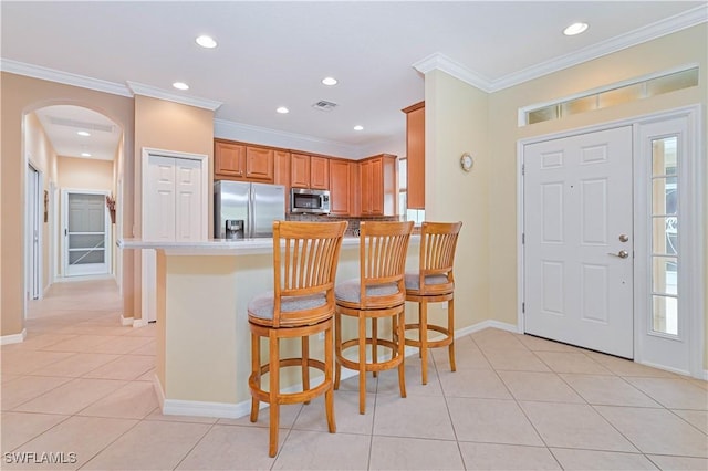 kitchen featuring a breakfast bar, stainless steel appliances, kitchen peninsula, and crown molding