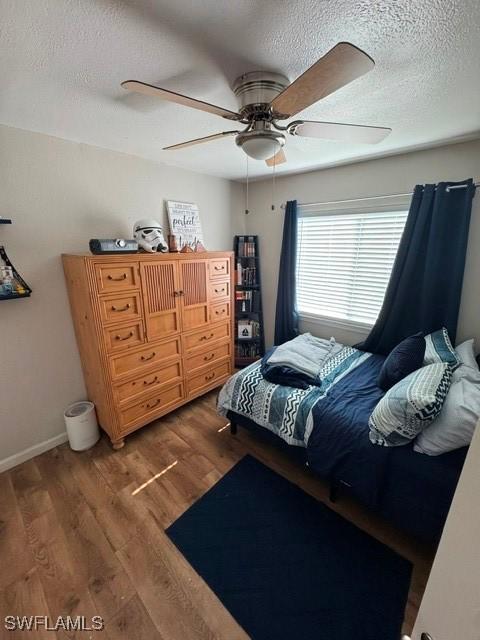 bedroom featuring ceiling fan, dark wood-type flooring, and a textured ceiling