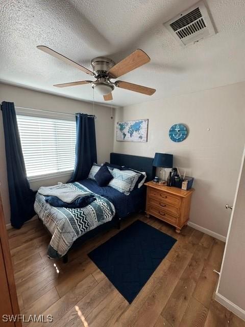 bedroom with wood-type flooring, a textured ceiling, and ceiling fan