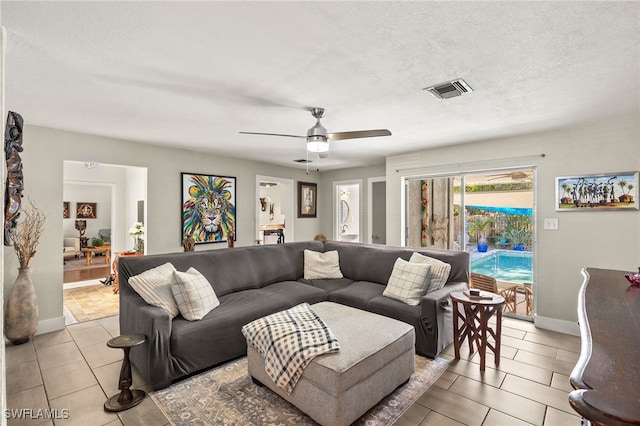 tiled living room with ceiling fan and a textured ceiling