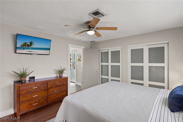 bedroom with ceiling fan, dark hardwood / wood-style floors, and a textured ceiling