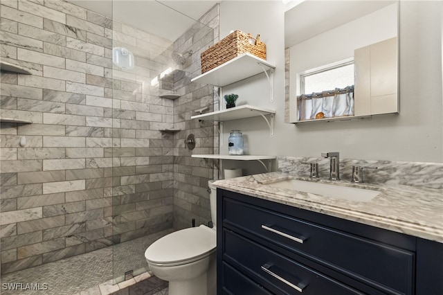 bathroom featuring vanity, toilet, and tiled shower