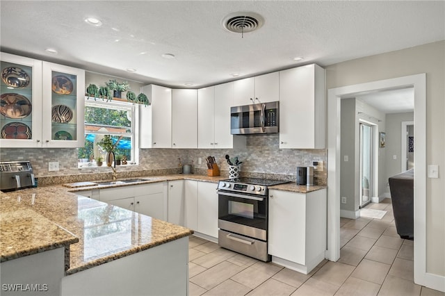 kitchen featuring white cabinets, light stone countertops, appliances with stainless steel finishes, and sink