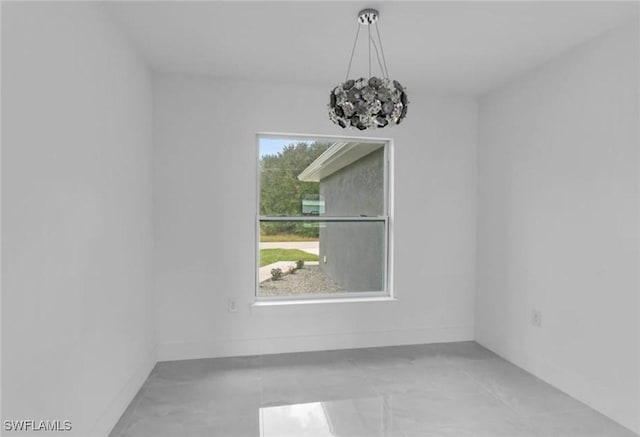 unfurnished room with a chandelier