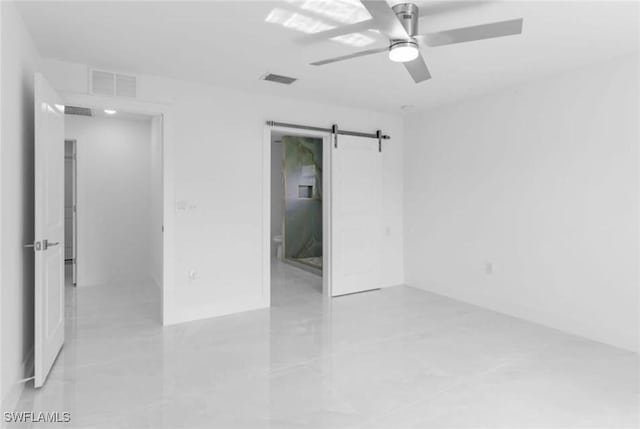 unfurnished room with a barn door and ceiling fan