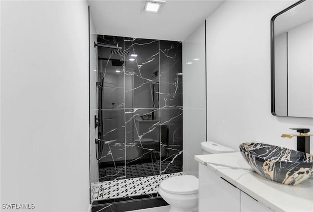 bathroom with tiled shower, vanity, and toilet