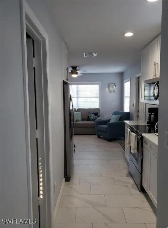 kitchen with white cabinets, ceiling fan, and stainless steel appliances