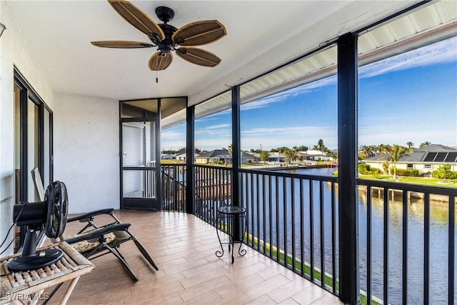 sunroom / solarium with a water view and ceiling fan