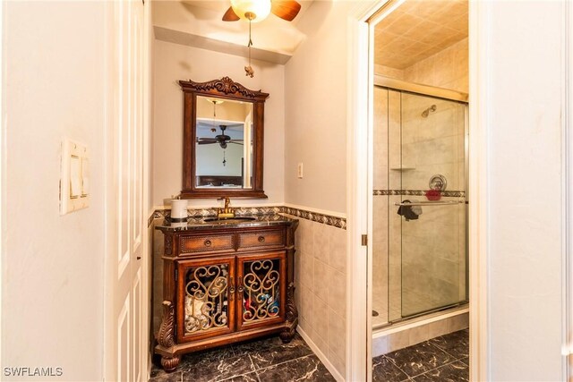 bathroom featuring vanity, a shower with door, and tile walls