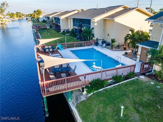 pool with a patio, a lawn, and a water view