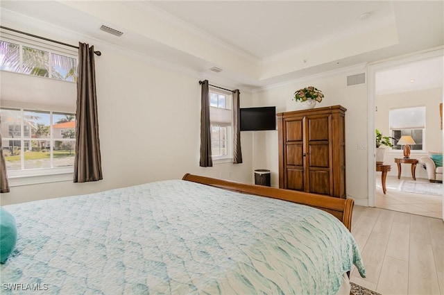 bedroom with a raised ceiling, light hardwood / wood-style flooring, and ornamental molding