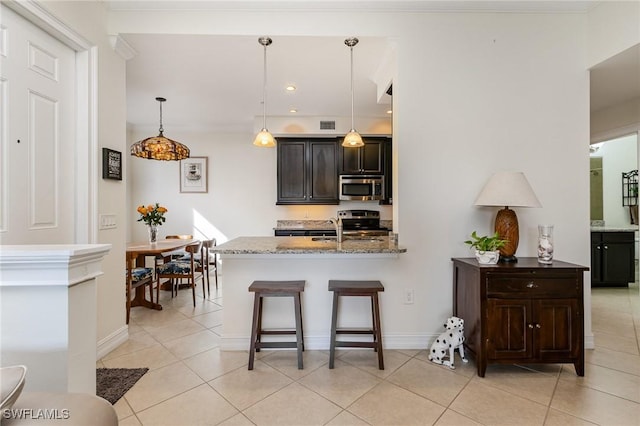 kitchen featuring light stone counters, dark brown cabinets, light tile patterned flooring, and stainless steel appliances