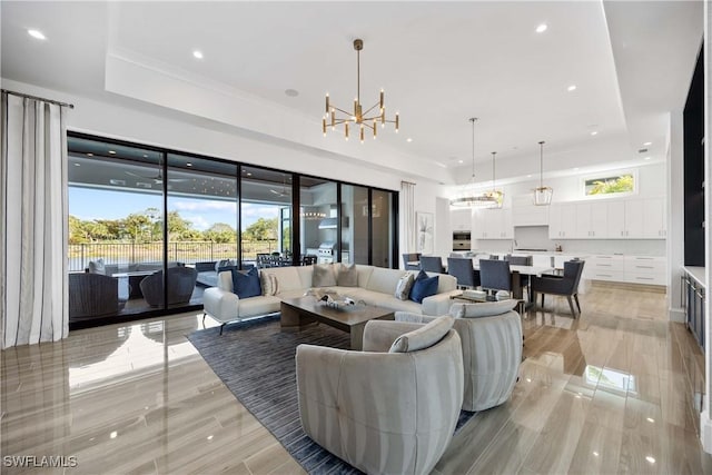 living room with a healthy amount of sunlight, a raised ceiling, and a chandelier