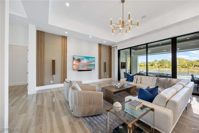 living room with light hardwood / wood-style floors, a raised ceiling, and a notable chandelier