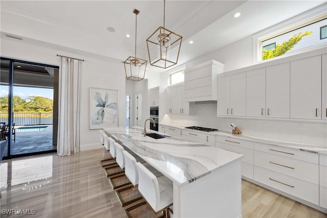 kitchen featuring white cabinets, a breakfast bar, a center island with sink, and gas stovetop