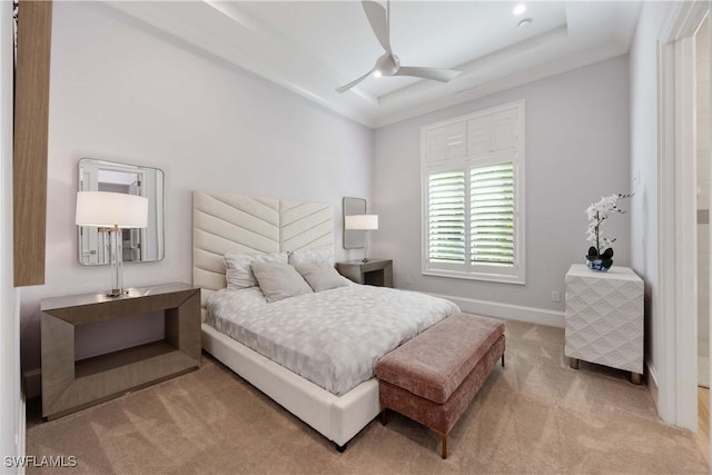 carpeted bedroom featuring a tray ceiling and ceiling fan