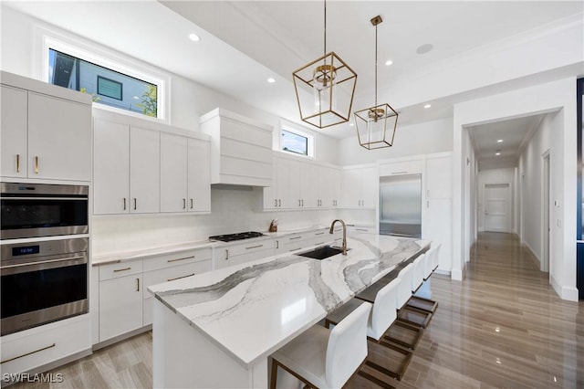 kitchen featuring white cabinets, an island with sink, and sink