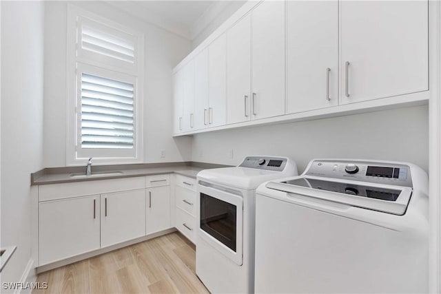 laundry area featuring cabinets, ornamental molding, washer and clothes dryer, sink, and light hardwood / wood-style flooring