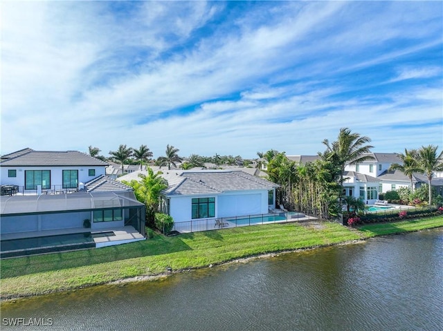 back of house featuring a water view, glass enclosure, a lawn, and a swimming pool