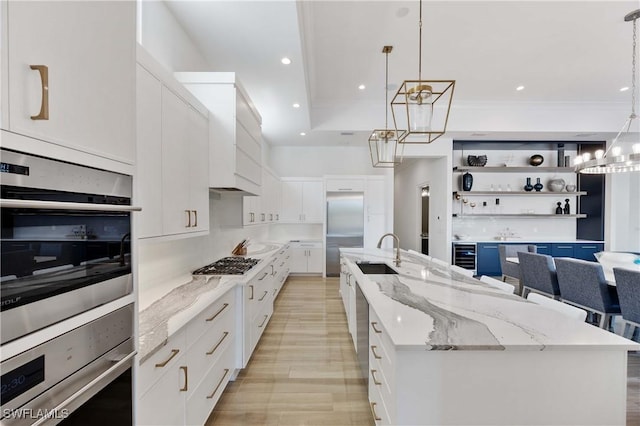 kitchen with decorative light fixtures, a spacious island, white cabinetry, and sink