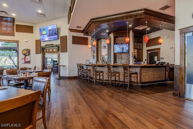 bar with pendant lighting, a towering ceiling, and hardwood / wood-style floors