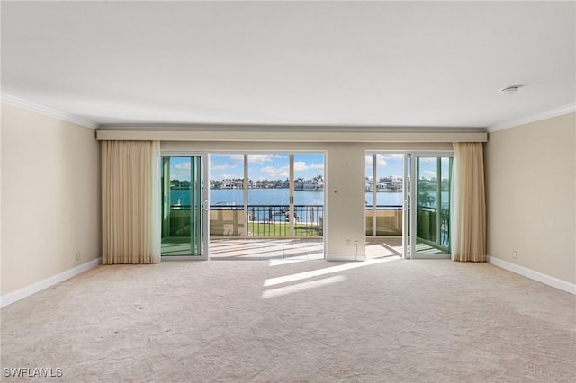 empty room featuring ornamental molding, baseboards, a water view, and carpet flooring