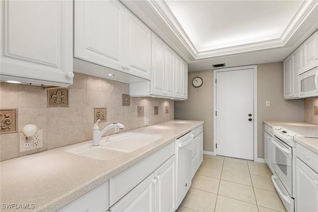 kitchen with white appliances, a sink, white cabinets, light countertops, and tasteful backsplash