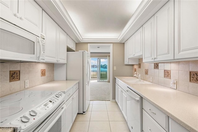 kitchen with white appliances, light tile patterned flooring, a sink, and white cabinets