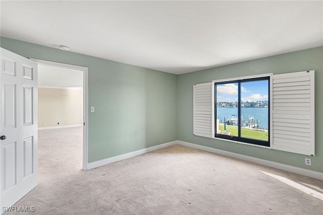 unfurnished room with a water view, baseboards, and carpet flooring