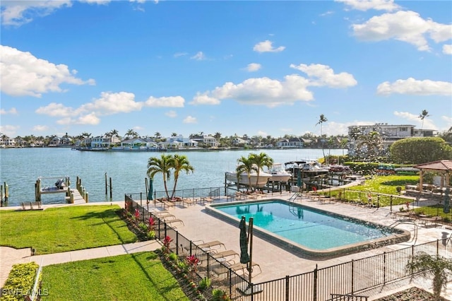 view of swimming pool featuring a water view, a boat dock, fence, and a lawn