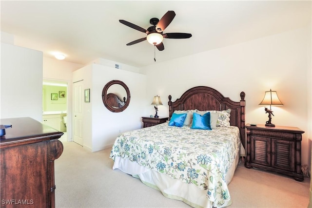 bedroom with a closet, ensuite bathroom, ceiling fan, and light colored carpet