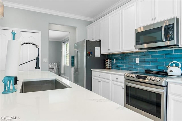 kitchen featuring white cabinetry, stainless steel appliances, tasteful backsplash, sink, and ornamental molding