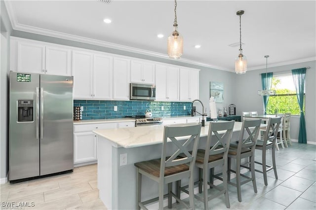 kitchen with hanging light fixtures, white cabinets, a kitchen island with sink, and appliances with stainless steel finishes