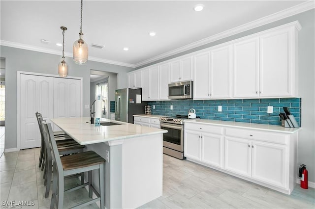 kitchen with white cabinetry, stainless steel appliances, an island with sink, sink, and hanging light fixtures