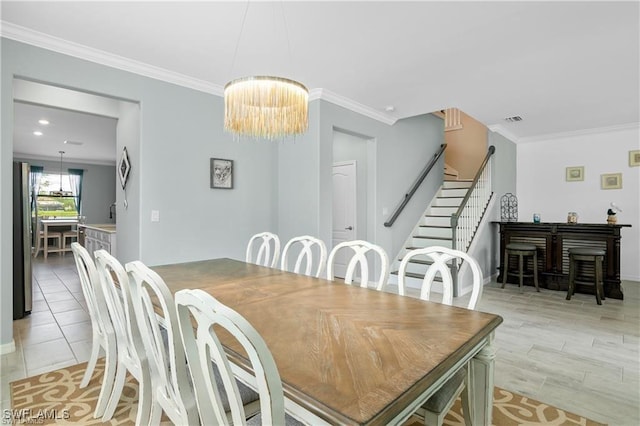 dining space featuring light hardwood / wood-style flooring, crown molding, and a chandelier