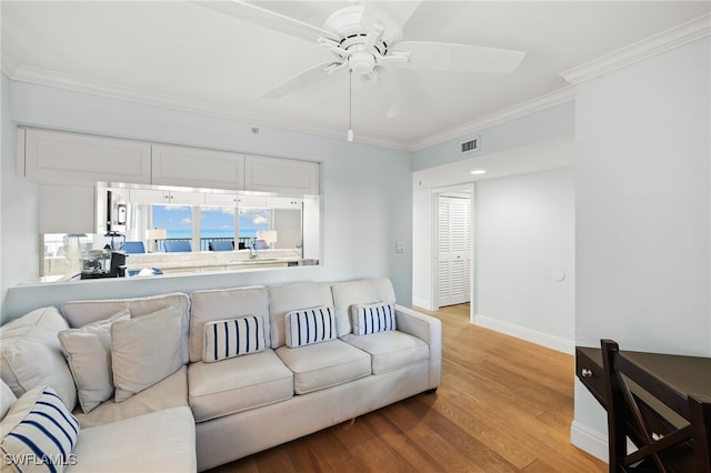 living area with light wood finished floors, baseboards, visible vents, a ceiling fan, and ornamental molding