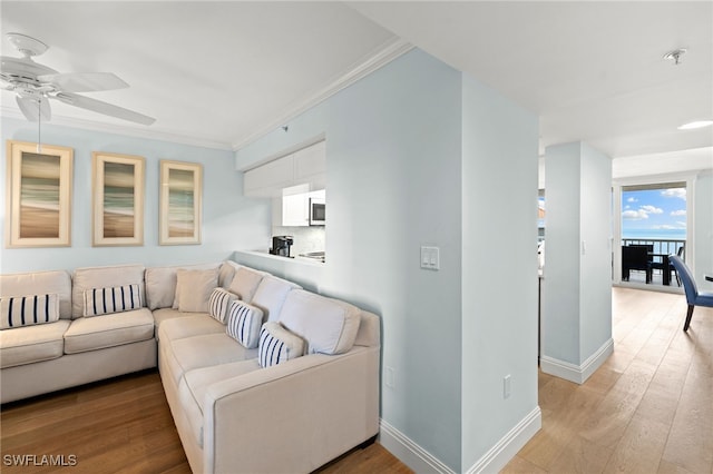 living area with light wood-type flooring, baseboards, and crown molding