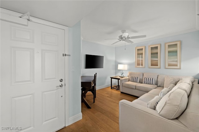 living room with baseboards, wood finished floors, a ceiling fan, and crown molding