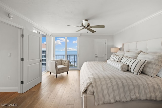 bedroom with ornamental molding, access to outside, a water view, and wood finished floors