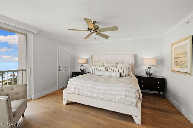 bedroom with baseboards, wood finished floors, a water view, access to outside, and crown molding